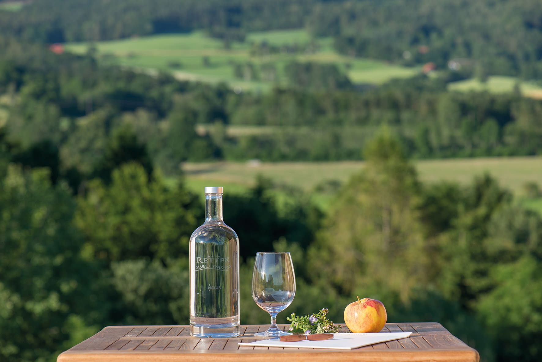 Wasserflasche mit Glas und Apfel auf Tisch